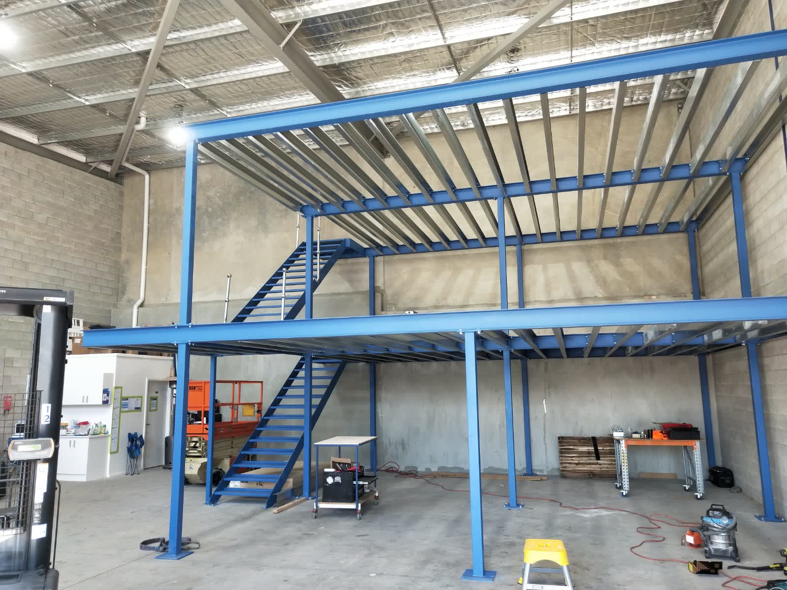 Mezzanine floor expanding vertical capacity — shows the relationship between ground floor operations and the raised level, demonstrating the spatial gain rather than just the structure