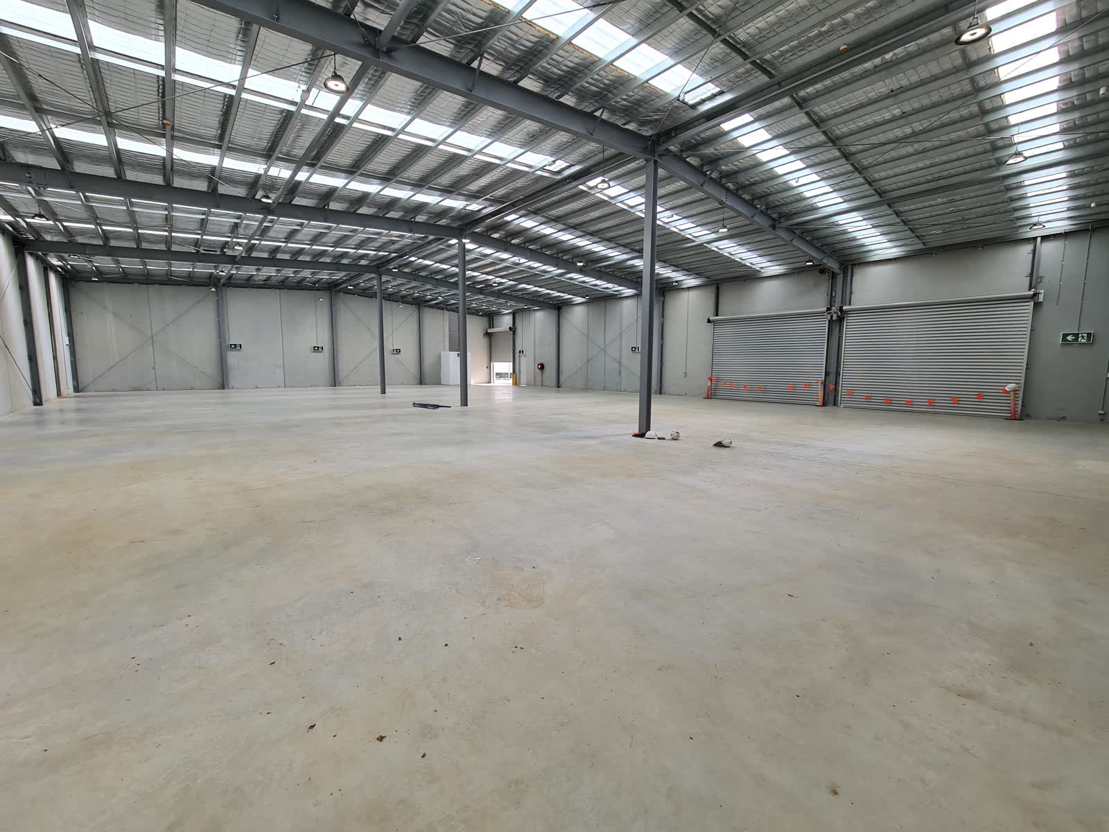 Warehouse Relocation 1 New site being planned before move-in — someone reviewing a floor plan in an empty warehouse, showing the decision-making stage rather than the completed installation